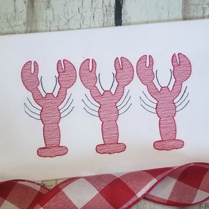 May include: Three red embroidered lobsters with black outlines on a white background.