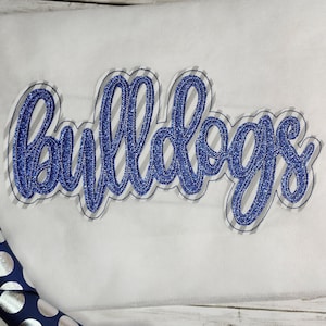 May include: Blue and gray embroidered "Bulldogs" text on a white fabric background.