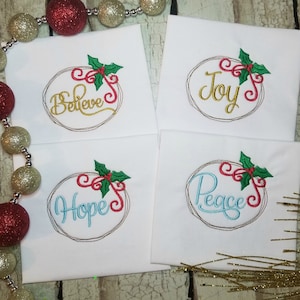 May include: Four white embroidered tea towels with a Christmas wreath design. Each towel features a different word: Believe, Joy, Hope, and Peace. The wreaths are decorated with red and green holly and candy canes.