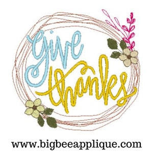 May include: A wreath with a brown twig design and a blue and yellow embroidered "give thanks" message. The wreath is decorated with small white flowers and green leaves.