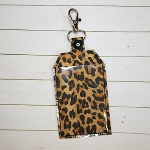 May include: A leopard print key chain with a clear plastic window and a silver metal clip.