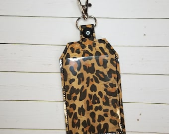 May include: A leopard print key chain with a clear plastic window and a silver metal clip.