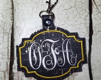 May include: A black and gold key chain with a cork-like texture and a white monogram "OFA".