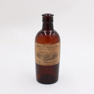 May include: A vintage brown glass bottle with a label that reads "PARKE, DAVIS & CO." The bottle has a rounded body and a narrow neck. The label is a light brown color with black text. The bottle is likely an antique pharmaceutical container.