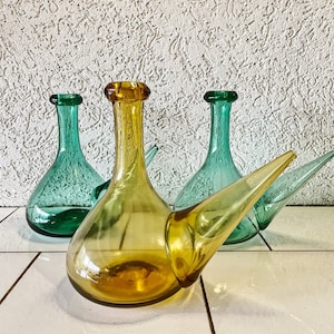 Puede incluir: Tres botellas de vidrio con un pico, dos son verdes y una es ámbar.