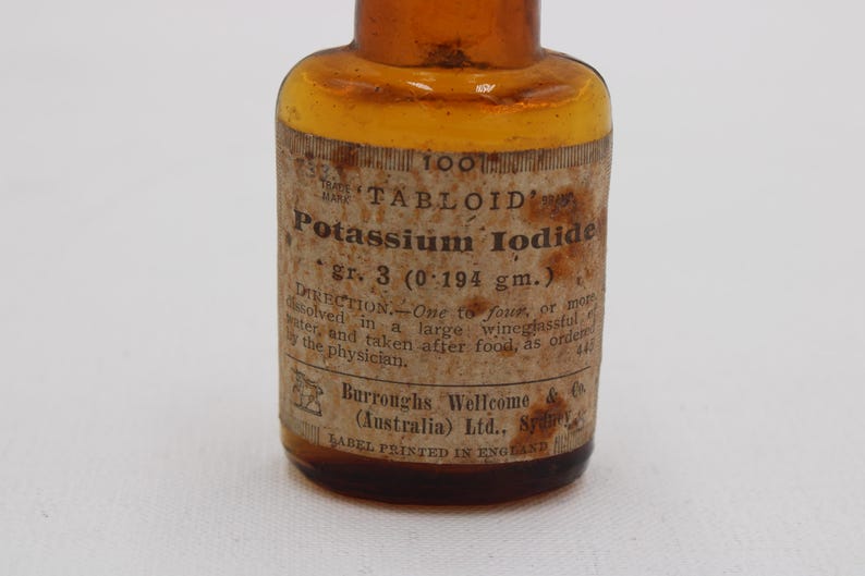 Puede incluir: Una antigua botella de vidrio &aacute;mbar con una etiqueta de papel. La etiqueta dice "TABLOID Potassium Iodide gr. 3 (0,194 g)" e incluye instrucciones de uso. La botella es probablemente de principios del siglo XX.