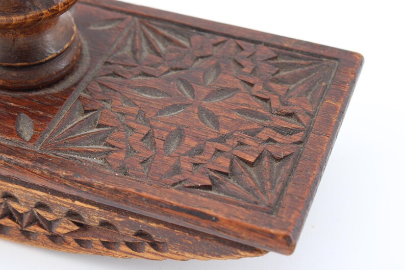 May include: Close-up of a vintage wooden inkwell with intricate carved floral and geometric patterns. The inkwell is a rich brown color, showcasing detailed craftsmanship and a classic design.