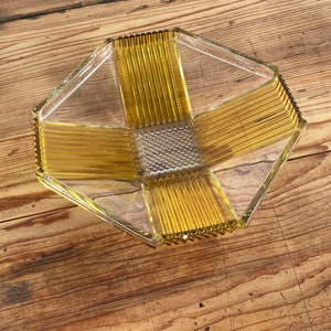 May include: A clear glass serving dish with a geometric design. The dish has a yellow-amber color and a textured surface.