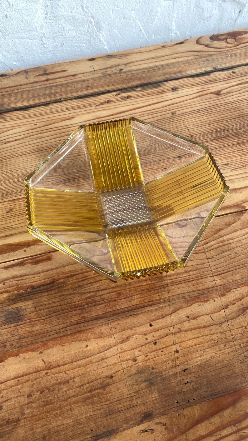 May include: A clear glass serving dish with a geometric design. The dish has a yellow-amber color and a textured surface.
