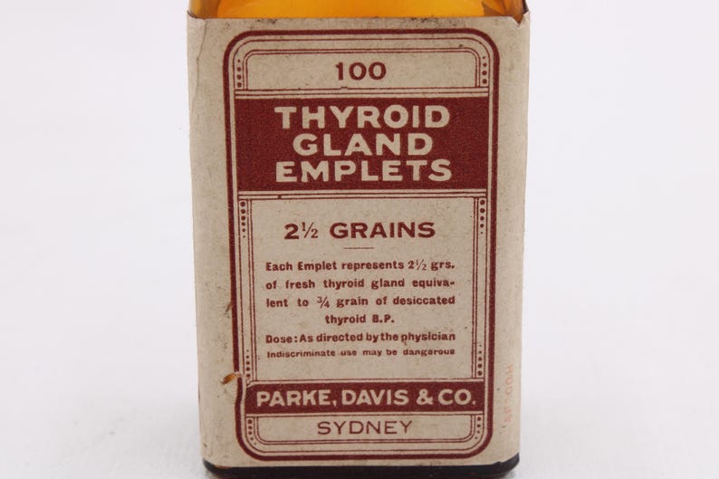 May include: An antique medicine bottle label for "Thyroid Gland Emplets." The label is primarily brown and cream-colored, with text in a vintage font. It includes the dosage information and the manufacturer's name, Parke, Davis & Co., Sydney.