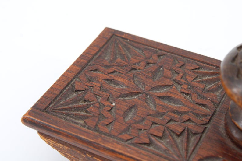 May include: Close-up of a dark brown wooden box with intricate floral carvings. The box has a rectangular shape with a detailed pattern of carved flowers and leaves. The wood has a rich, warm tone, and the carvings add depth and texture.