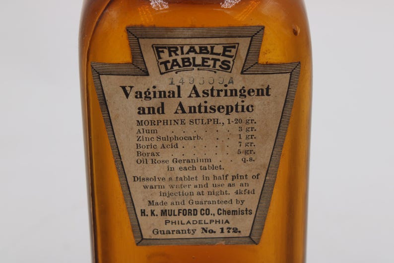 May include: An antique amber glass bottle with a paper label. The label reads "Friable Tablets Vaginal Astringent and Antiseptic." The label also lists ingredients and instructions. The bottle is likely from the early 20th century.