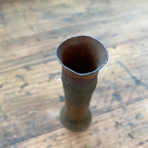 May include: A small, copper-colored vase with a flared top and a slightly textured surface.