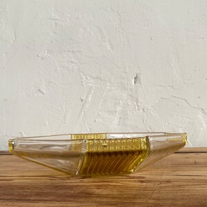 May include: A yellow glass serving dish with a geometric design. The dish is made of clear glass with a yellow tint and has a starburst pattern.