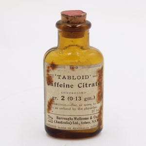 May include: An old amber glass bottle with a cork stopper. The bottle has a label with the text "TABLOID Caffeine Citrate" and "gr. 2 (0.13 gm.)". The label also includes the manufacturer's name and "MADE IN AUSTRALIA".