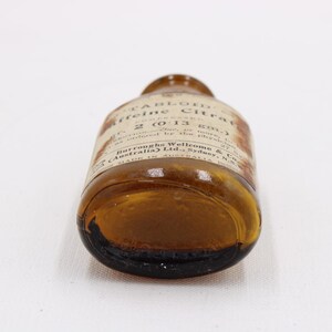 May include: An antique brown glass bottle with a label, lying on its side. The label reads "TABLOID Caffeine Citrate" and other text. The bottle is made in Australia.