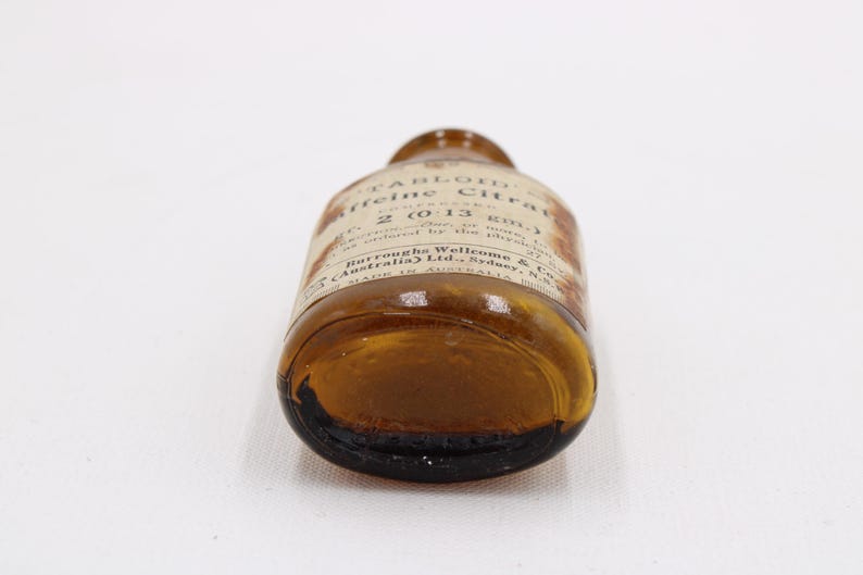 May include: An antique brown glass bottle with a label, lying on its side. The label reads "TABLOID Caffeine Citrate" and other text. The bottle is made in Australia.