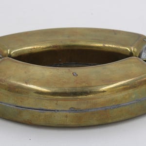 May include: A vintage brass flask with a hinged design. The flask has a rounded shape with a tarnished finish and two screw-on caps. The overall design is a classic, functional piece.