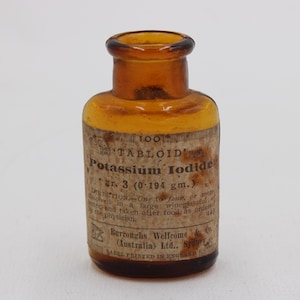Puede incluir: Una botella de vidrio &aacute;mbar con una etiqueta que dice "TABLOID Potassium Iodide". La etiqueta tambi&eacute;n incluye instrucciones de dosificaci&oacute;n y el nombre del fabricante, Burroughs Wellcome & Co. Es un antiguo envase farmac&eacute;utico.