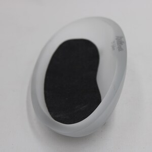 K&ouml;nnte beinhalten: Oval geformte Seifenschale aus mattiertem Glas mit schwarzem Einsatz. Die Schale hat ein glattes, geschwungenes Design und ein kleines Logo an der Seite. Die Seifenschale ist f&uuml;r Seifenst&uuml;cke konzipiert.