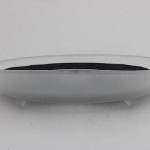 K&ouml;nnte beinhalten: Ovale Schale aus mattiertem Glas mit dunklem Innenraum. Die Schale hat eine glatte, matte Oberfl&auml;che und steht auf drei kleinen F&uuml;&szlig;en. Das Wort "Dresden" ist schwach auf der Seite zu sehen.