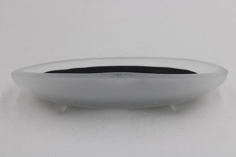 K&ouml;nnte beinhalten: Ovale Schale aus mattiertem Glas mit dunklem Innenraum. Die Schale hat eine glatte, matte Oberfl&auml;che und steht auf drei kleinen F&uuml;&szlig;en. Das Wort "Dresden" ist schwach auf der Seite zu sehen.
