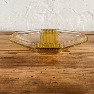 May include: A clear glass serving tray with a hexagonal shape and a raised, textured center section. The tray is a pale yellow color.