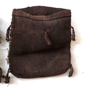 May include: A brown woven bag with a drawstring closure and two small tassels on the sides.