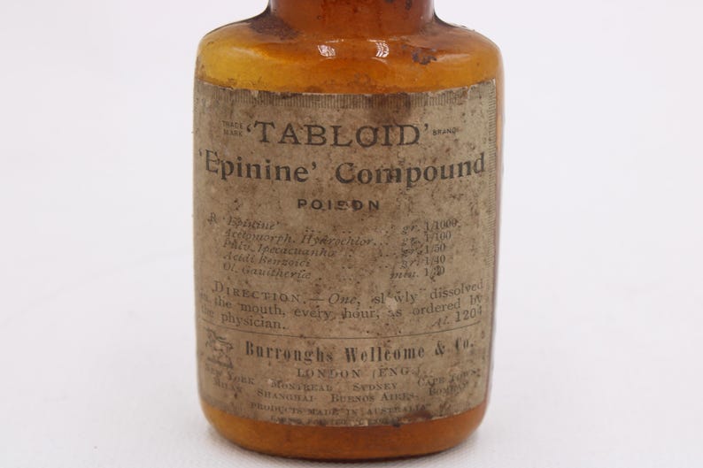 May include: An antique amber glass bottle with a paper label. The label reads "TABLOID Epinine Compound POISON" with detailed text and directions. The bottle has a vintage aesthetic, suggesting it is an old pharmaceutical item.