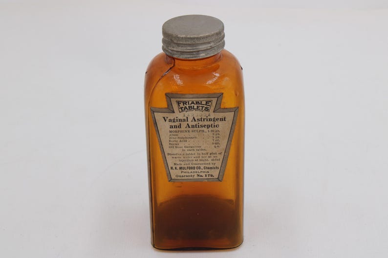 May include: An amber-colored glass bottle with a gray metal cap. The bottle has a label that reads "FRIABLE TABLETS Vaginal Astringent and Antiseptic." The label also lists ingredients and the manufacturer, K.K. Mulford Co., Philadelphia.