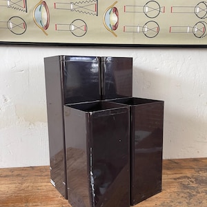 May include: A dark brown metal organiser with three compartments. The organiser is rectangular and has a glossy finish. The image also shows a vintage educational poster in the background.