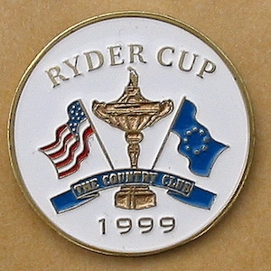 Peut inclure: Une épingle ronde blanche avec une bordure dorée. L'épingle présente le logo de la Ryder Cup, y compris le trophée de la Ryder Cup, deux drapeaux et le texte "RYDER CUP". Le texte "THE COUNTRY CLUB" et l'année "1999" sont également inclus sur l'épingle.