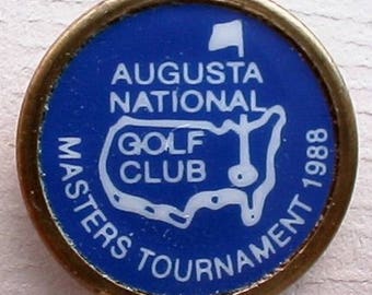 May include: A blue and gold golf tournament pin with the text "Augusta National Golf Club Masters Tournament 1988" and a white outline of the United States.