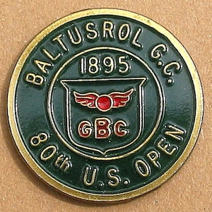 Op de afbeelding: Een groene en gouden golftoernooi-gedenkmunt met de tekst " Baltusrol G.C. 1895 80th U.S. Open" en een schild met de letters "GBC" en een rood gevleugeld logo.