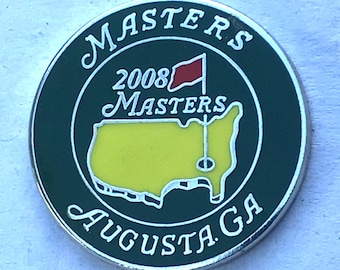 Puede incluir: Un marcador de bola de golf verde y negro con las palabras "Masters 2008 Masters Augusta GA" y un contorno amarillo de los Estados Unidos con una bandera roja.