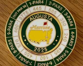 May include: A gold-colored golf ball marker with the Augusta Masters logo, a yellow map, and the text "2025." The marker also displays hole numbers, par values, and yardages, including "1-PAR4 445" and "2-PAR5 585."
