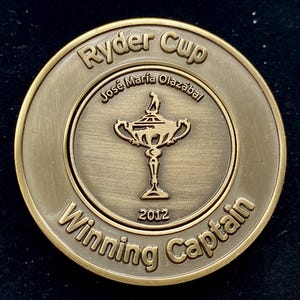 Op de afbeelding: Een gouden Ryder Cup-munt ter herdenking van de Ryder Cup van 2012. De munt toont de Ryder Cup-trofee en de tekst "Ryder Cup", "José María Olazábal" en "Winning Captain".