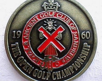 Op de afbeelding: Een bronzen medaille met een rood en wit kruis in het midden. De tekst rond het kruis luidt "The Open Golf Championship 1960 The Royal Ancient Golf Club of St Andrews".
