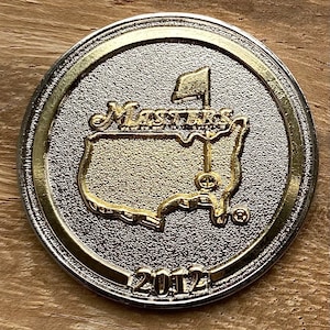 Op de afbeelding: Een zilveren en gouden munt met het Masters Tournament-logo en het jaar 2012.