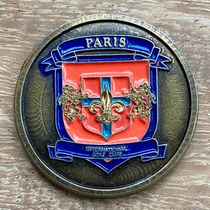 Magnífico marcador de pelota de golf de latón pintado a mano del Paris International Golf Club. Moneda de regalo para golf. Raro marcador de pelota de golf de USA Golfdesign de 30 años de antigüedad.