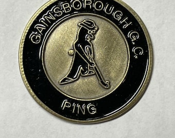 Peut inclure: Un marqueur de balle de golf de couleur dorée avec un anneau noir autour du bord. Le centre présente une illustration en noir et blanc d'un golfeur avec un chapeau et un club de golf. Le texte "GAINSBOROUGH G.C." est écrit autour du haut de l'anneau et "PING" est écrit en bas.