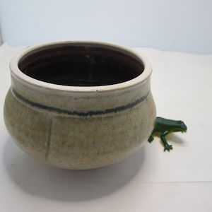 May include: A white ceramic bowl with a brown rim and a black stripe around the middle. The bowl is sitting on a white surface.