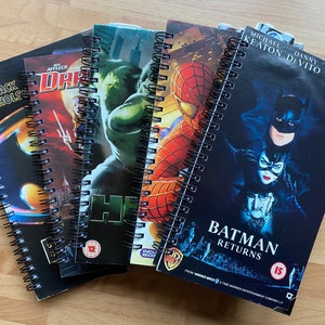 May include: A collection of four spiral-bound notebooks featuring film-themed covers. The notebooks display artwork and titles including Batman Returns with Michael Keaton, Danny DeVito, and Michelle Pfeiffer, Spider-Man, Hulk, and Daredevil with Jack Nicholson.