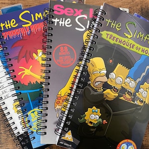 May include: Three spiral-bound notebooks featuring The Simpsons themes. One cover shows a height chart, another depicts Sideshow Bob, and the third displays a Treehouse of Horror scene with Homer, Bart, Marge, and Lisa in a dark, spooky setting.
