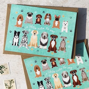 May include: Two greeting cards with illustrations of various dog breeds on a teal background. The cards have the text "a little note to say..." and are in brown envelopes. Stamps and paperclips are also visible.