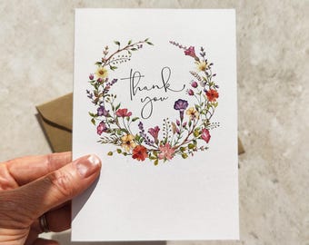 Delicadas tarjetas y sobres de agradecimiento doblados con flores