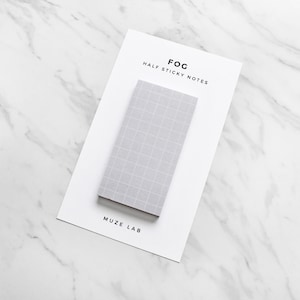 May include: A pack of half sticky notes with a grid pattern on the paper. The pack is labeled "FOG HALF STICKY NOTES" and "MUZE LAB".
