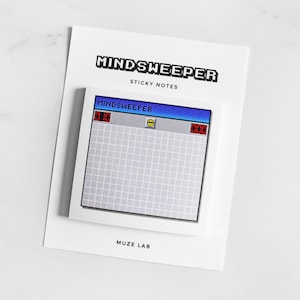 Puede incluir: Un bloc de notas adhesivas cuadrado con una interfaz de juego retro de Buscaminas que incluye una cuadrícula, un icono de cara sonriente y contadores digitales. El empaque es de cartulina blanca con el texto MINDSWEEPER STICKY NOTES y MUZE LAB.