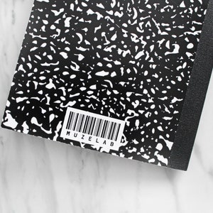 May include: Black and white composition notebook with a black spine and a barcode with the text "MUZELAB" printed on the back cover.