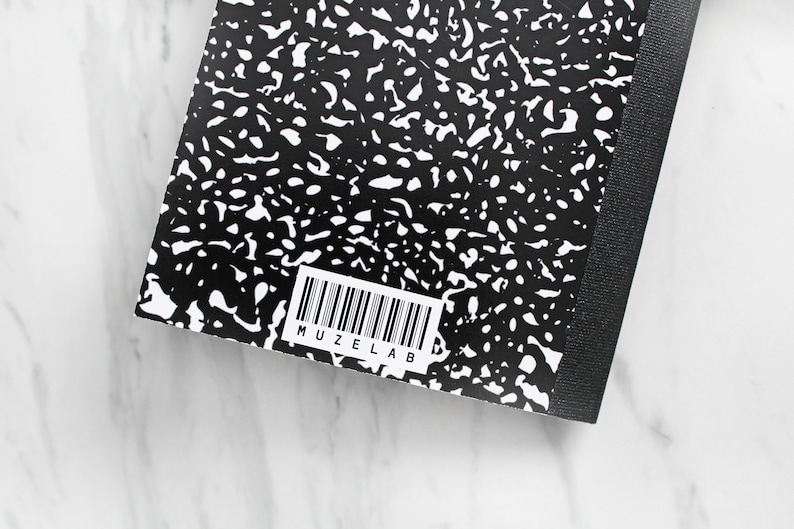 May include: Black and white composition notebook with a black spine and a barcode with the text "MUZELAB" printed on the back cover.